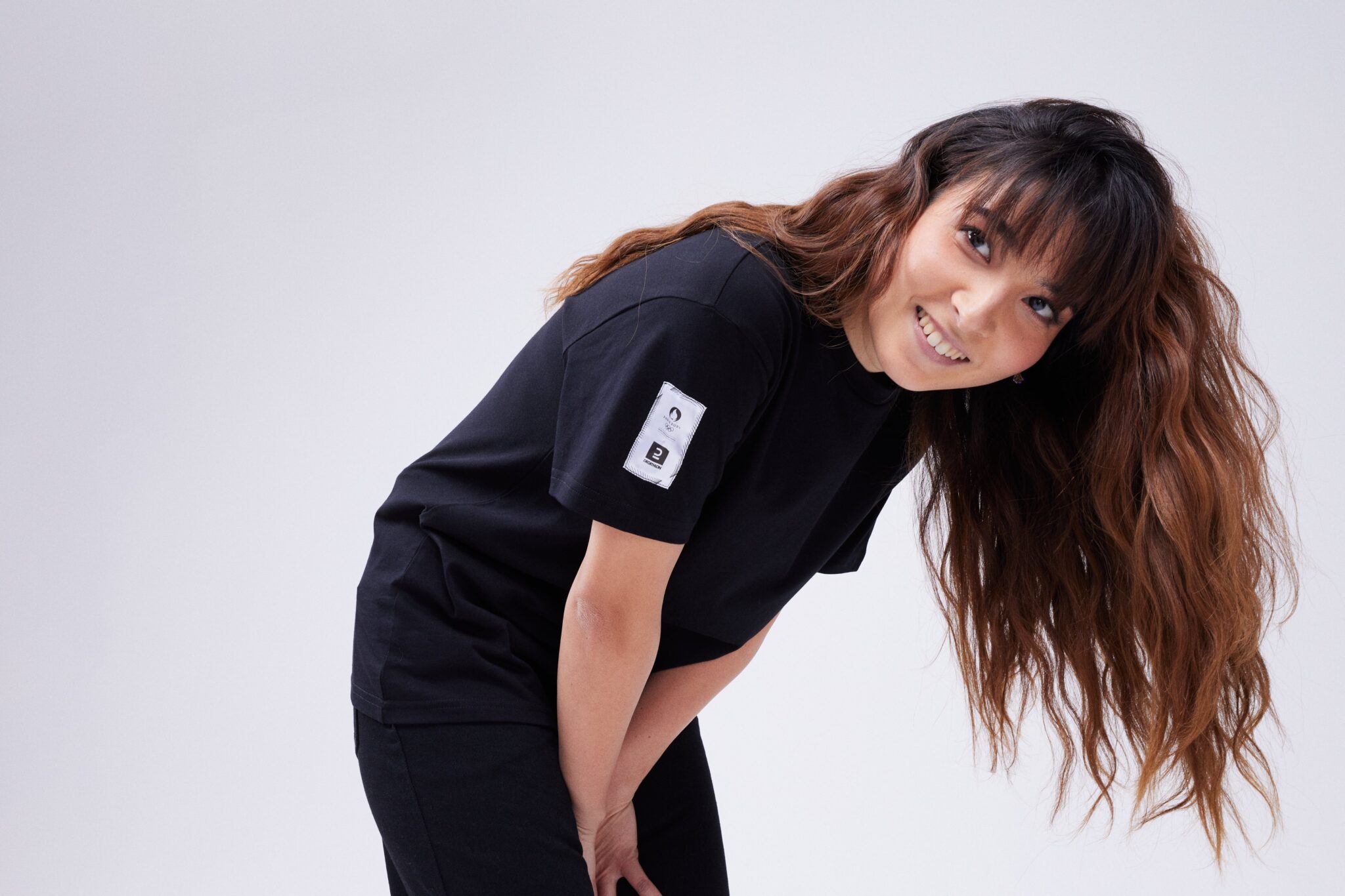 Photo Tijana Stojkovic, courbée, pour la nouvelle collection.Elle porte un t-shirt noir avec écrit Rêve Crew.