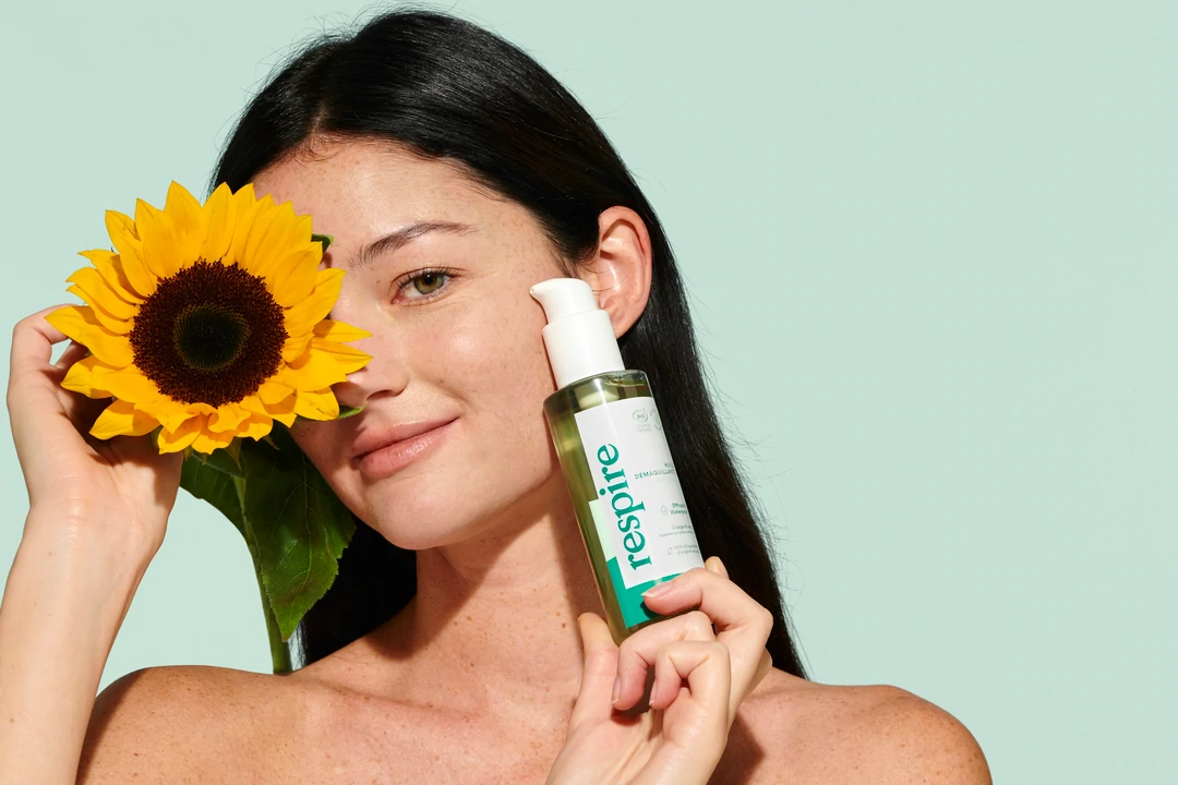 Mannequin sur un fond vert avec une fleur de tournesol et l'huile démaquillante de chez respire